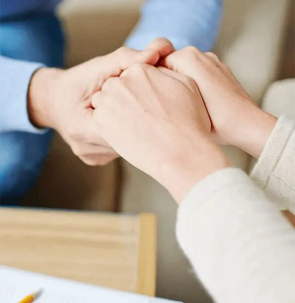 Two people holding hands while sitting at a table.